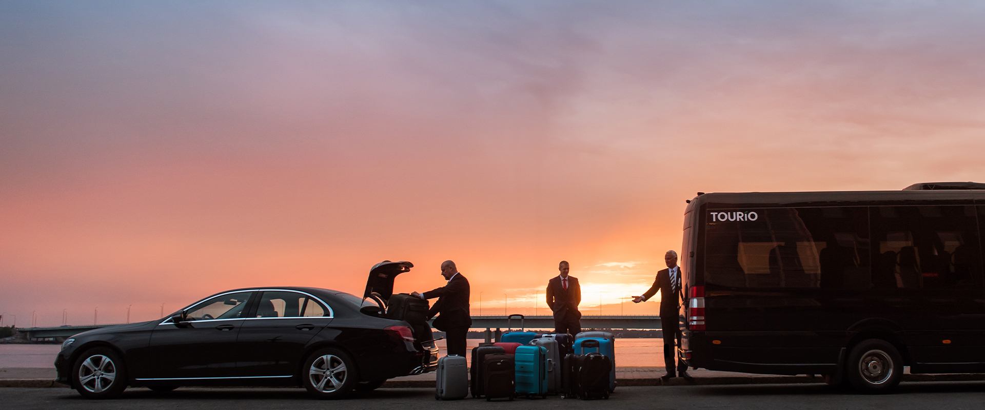 Autot, matkustajat ja matkalaukut auringonlaskussa.